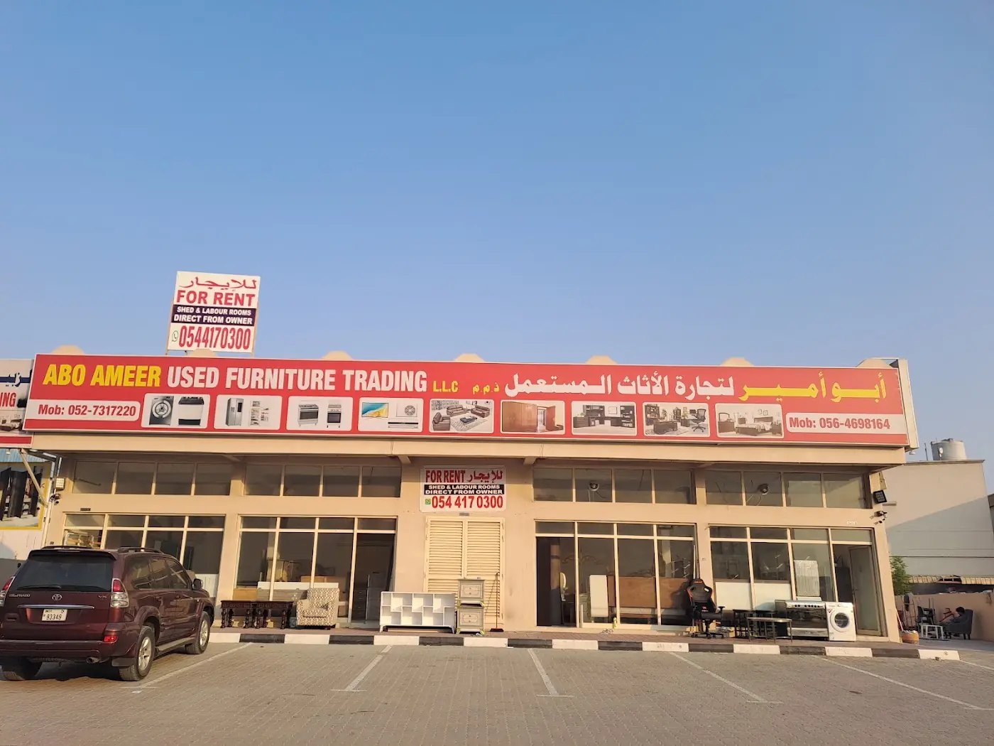 Abo Ameer Used Furniture Trading L.L.C. warehouse front with its sign in English and Arabic